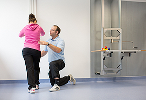 Ein Physiotherapeut hilft einer Patientin bei einer Übung.