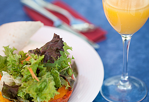 Ein Salatteller und ein Glas Orangensaft stehen auf einem Tisch.