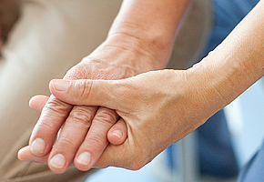 Eine Therapeutin hält die Hand einer Patientin.