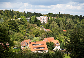 Blick über Wohnhäuser und Wald auf die Rehaklinik Heidelberg-Königstuhl.